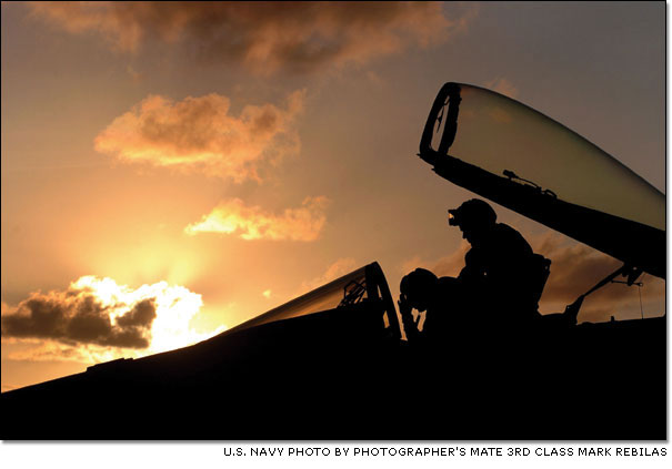 Technicians inspect the cockpit of a U.S. Navy F/A-18C Hornet