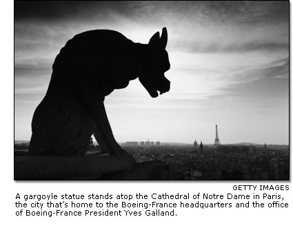 A gargoyle statue stands atop the Cathedral of Notre Dame in Paris